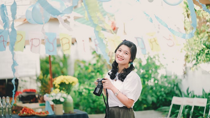 Young woman holding a camera in a colorful garden