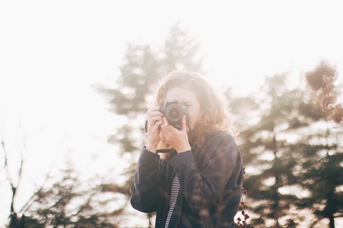 Young woman outside taking a picture of the photographer with one of the best camera for Instagram choicesth a camera