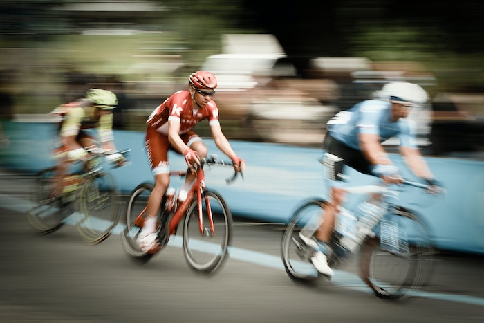 A blurred image of three cyclists racing on a road